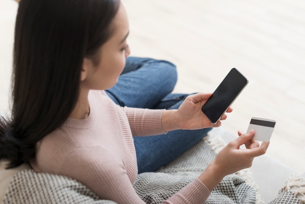 High angle of woman holding credit card and smartphone