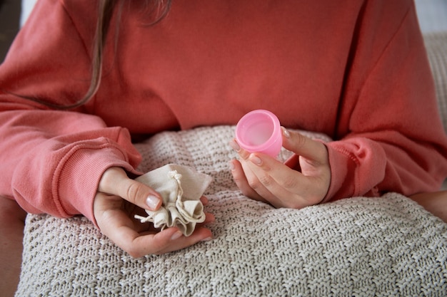 High angle woman holding menstrual cup and bag