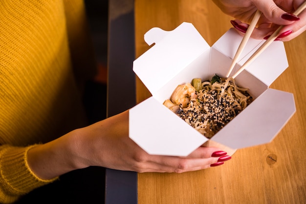 Free photo high angle of woman holding noodles box