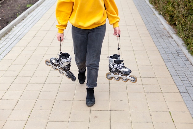 High angle on woman holding roller blades while walking