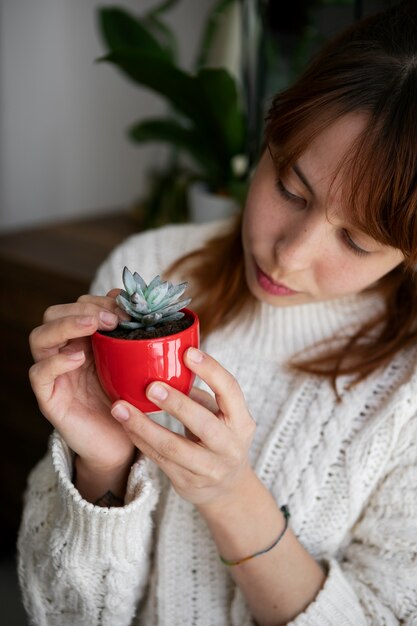 小さな植物を保持している高角度の女性