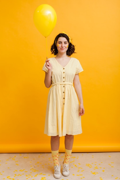 Free photo high angle woman holding yellow balloon