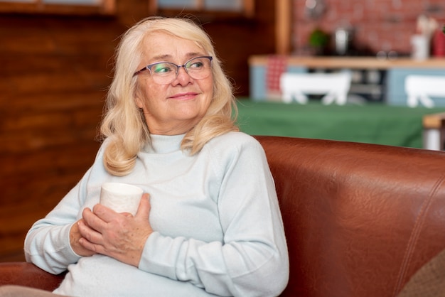 Free photo high angle woman at home drinking tea