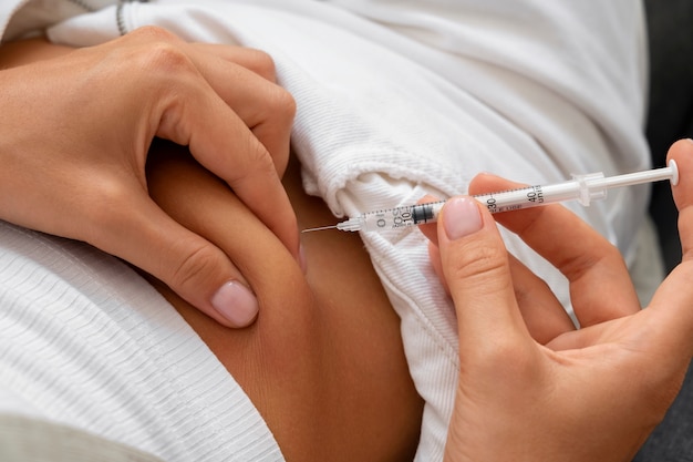 Free photo high angle woman injecting insulin at home