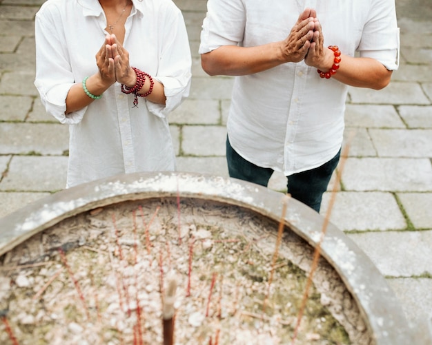 High angle of woman and man praying at the temple with burning incense