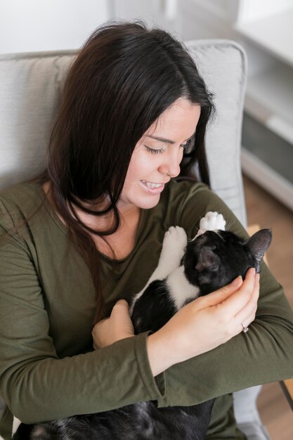 High angle woman playing with cat sitting on chair