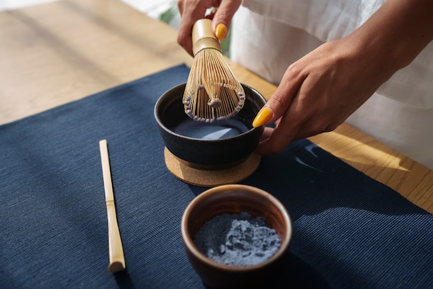 Foto gratuita donna dell'angolo alto che prepara matcha blu a casa