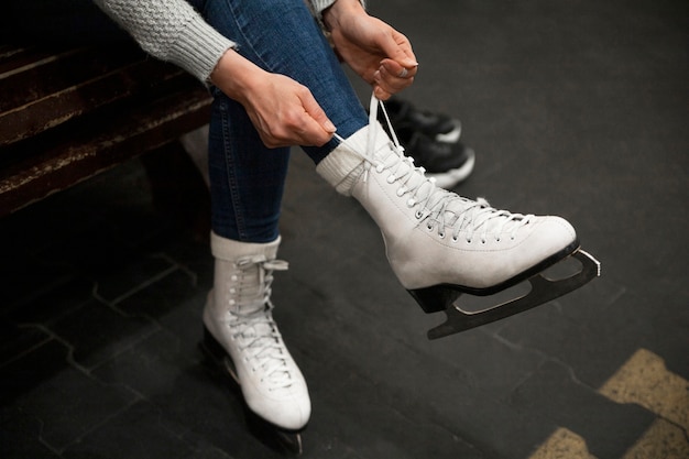 Free photo high angle woman putting on ice skates