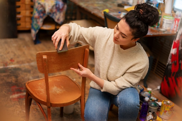 Женщина под высоким углом восстанавливает деревянный стул