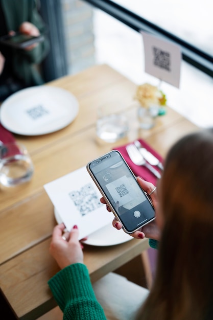 High angle woman scanning qr code at restaurant