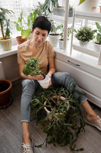 Высокий угол женщины, заботящейся о комнатных растениях