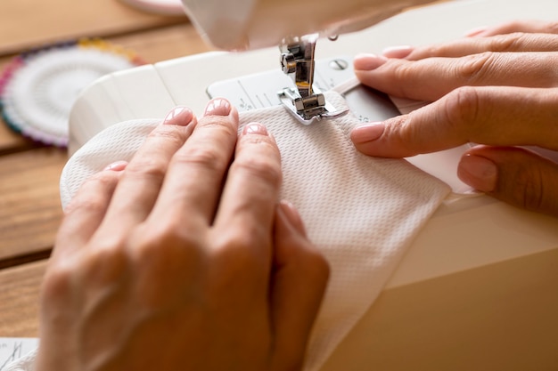 High angle of woman using sewing machine for face mask