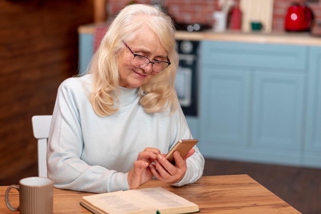 Foto gratuita donna dell'angolo alto che per mezzo dello smartphone