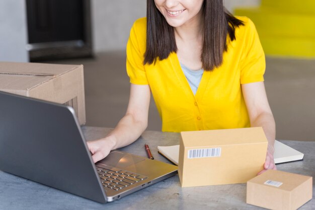High angle of woman with boxes and laptop