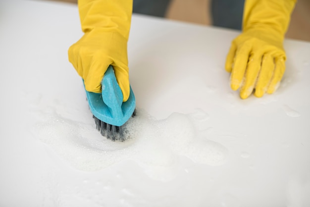 High angle of woman with cleaning gloves using brush