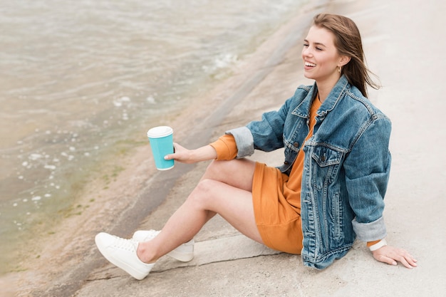 海辺でコーヒーを飲みながらハイアングルの女性