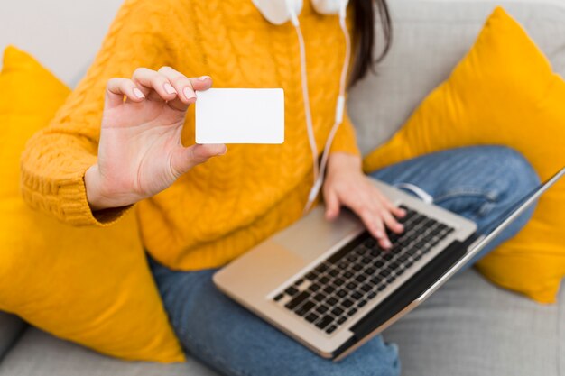 High angle of woman with laptop on lap showing credit card