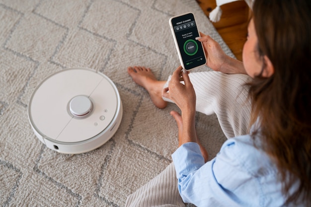 Free photo high angle woman with  robotic vacuum cleaner