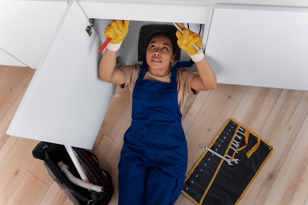Free photo high angle woman working as plumber