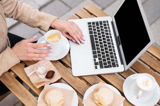 High angle of woman working on laptop outdoors while having lunch