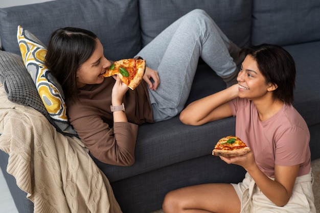 Free photo high angle women eating delicious pizza