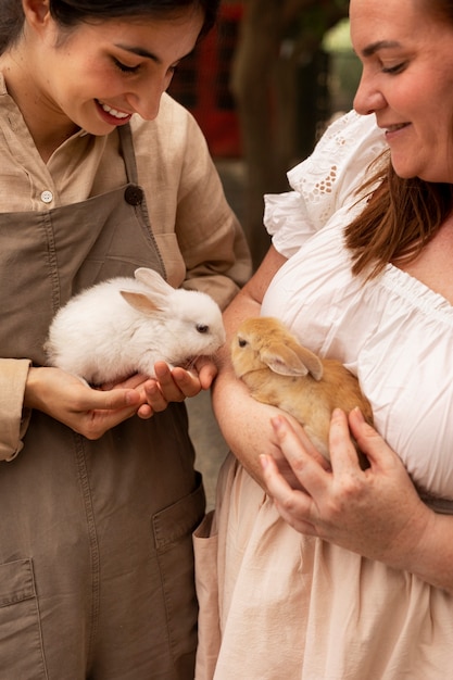 Free photo high angle women holding cute bunnies