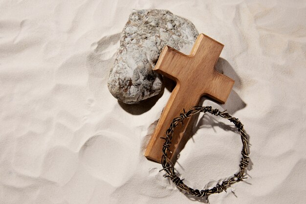 High angle wooden cross and crown of thorns on sand