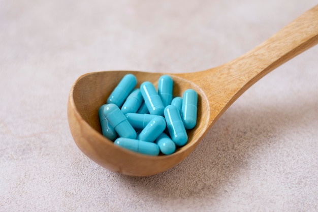 High angle wooden spoon with blue pills