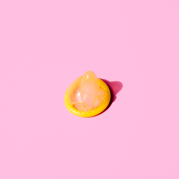 Бесплатное фото Высокий угол желтый презерватив на розовом фоне