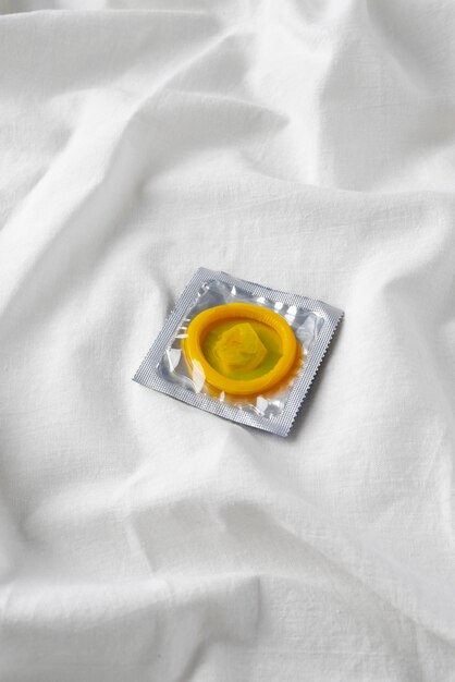 High angle yellow condom on sheet