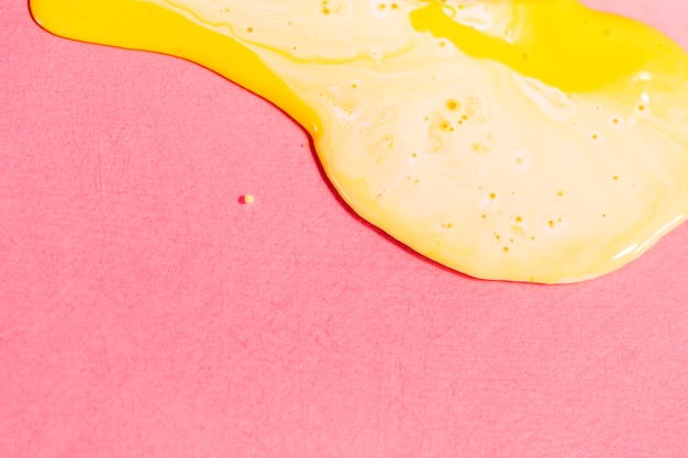High angle yellow paint on pink background