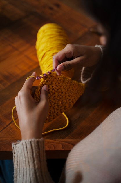 Free photo high angle young adult crocheting at home