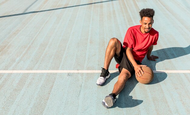 Молодой человек под высоким углом на баскетбольном поле с копией пространства
