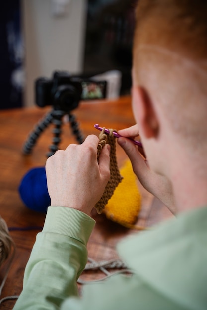 Free photo high angle young man knitting on camera