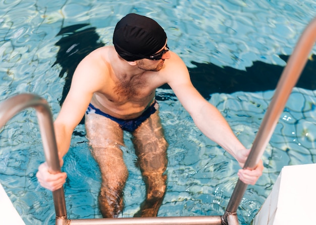 High angle young swimmer taking out of pool