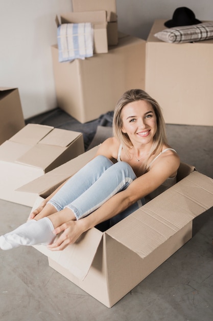 High angle young woman sitting in a box