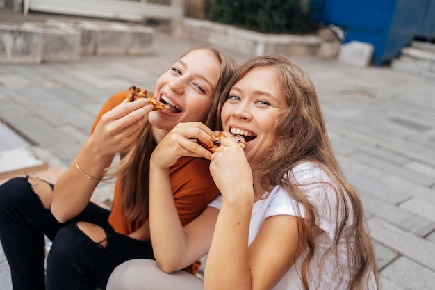 High angle young women eating pizza together