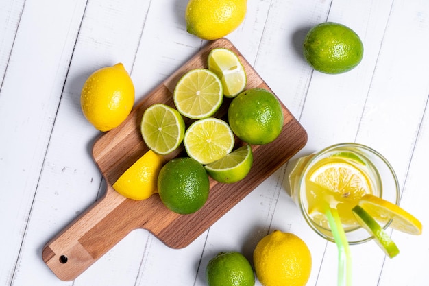 High anglw shot of lemons and limes on the cutting board and on the table with lemon juice
