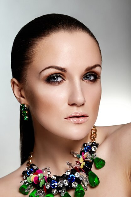 High fashion look. glamor closeup portrait of beautiful brunette Caucasian young woman model with healthy hair and green accessory jewelry