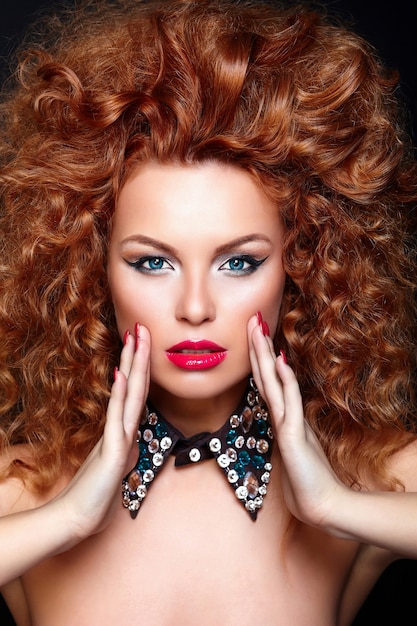 High fashion look.glamor closeup portrait of beautiful sexy redhead caucasian young woman model with red lips,bright makeup, with perfect clean skin with jewelery isolated on black