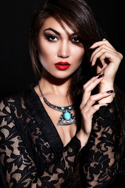 High fashion look.glamor closeup portrait of beautiful sexy stylish brunette Caucasian young woman model with bright makeup, with red lips,  with perfect clean skin with jewelery in black cloth