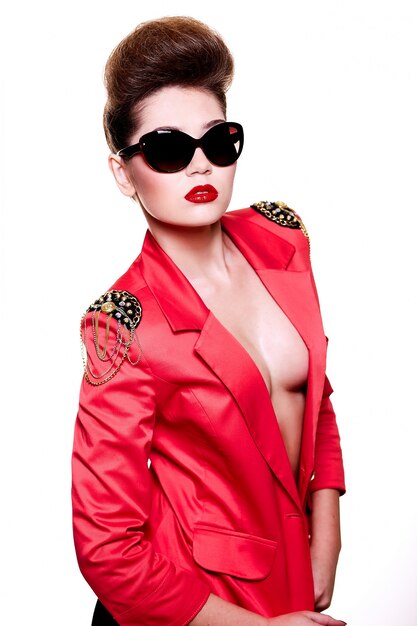 ファッション性の高い外観。サングラスの明るいピンクのジャケットの赤い唇と明るいメイクでセクシーなブルネットの白人若い女性の魅力のクローズアップの肖像画
