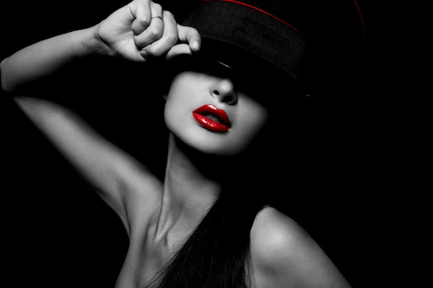 High fashion look.glamour portrait of beautiful sexy young female woman with red lips on black background with hat