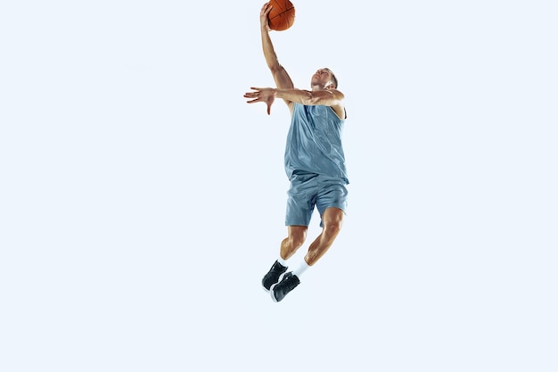 High flight. young caucasian basketball player of team in action, motion in jump isolated on white background. concept of sport, movement, energy and dynamic, healthy lifestyle. training, practicing.
