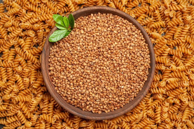 High resolution photo of buckwheat in a brown bowl in the middle of raw Italian pastas lined circle frame