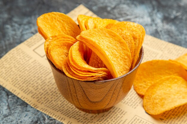 High resolution photo of delicious homemade chips on newspaper on gray table
