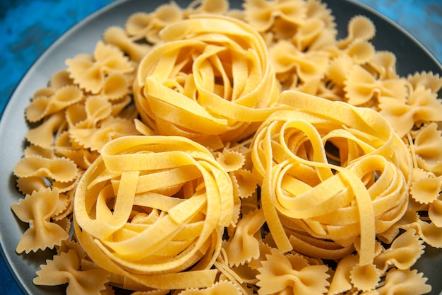 High resolution photo of dinner preparation with pasta noodles on a black plate on the left side on blue background