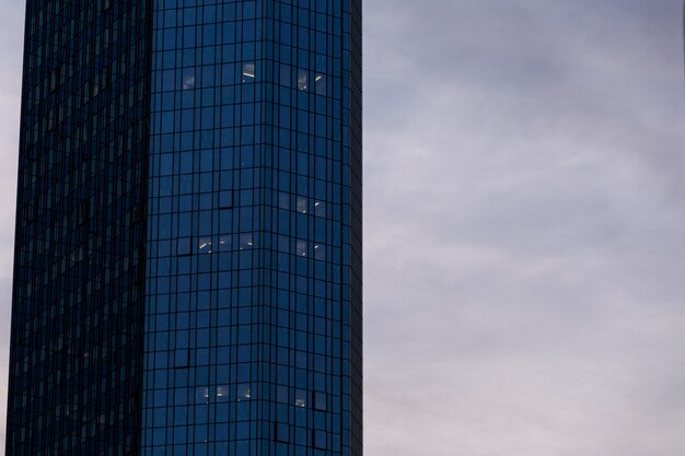 High-rise skyscraper in a glass facade under the cloudy sky in Frankfurt, Germany