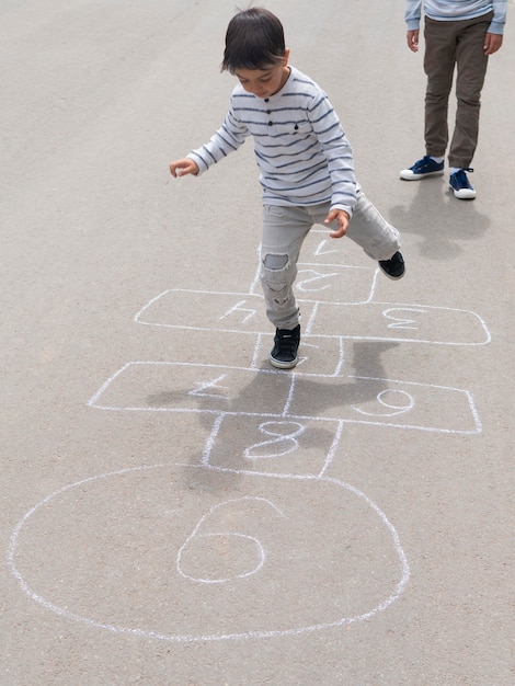 彼の兄弟と石けり遊びをする子供