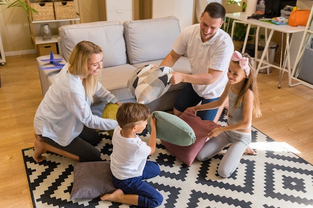 High view family playing in the living room with pillows